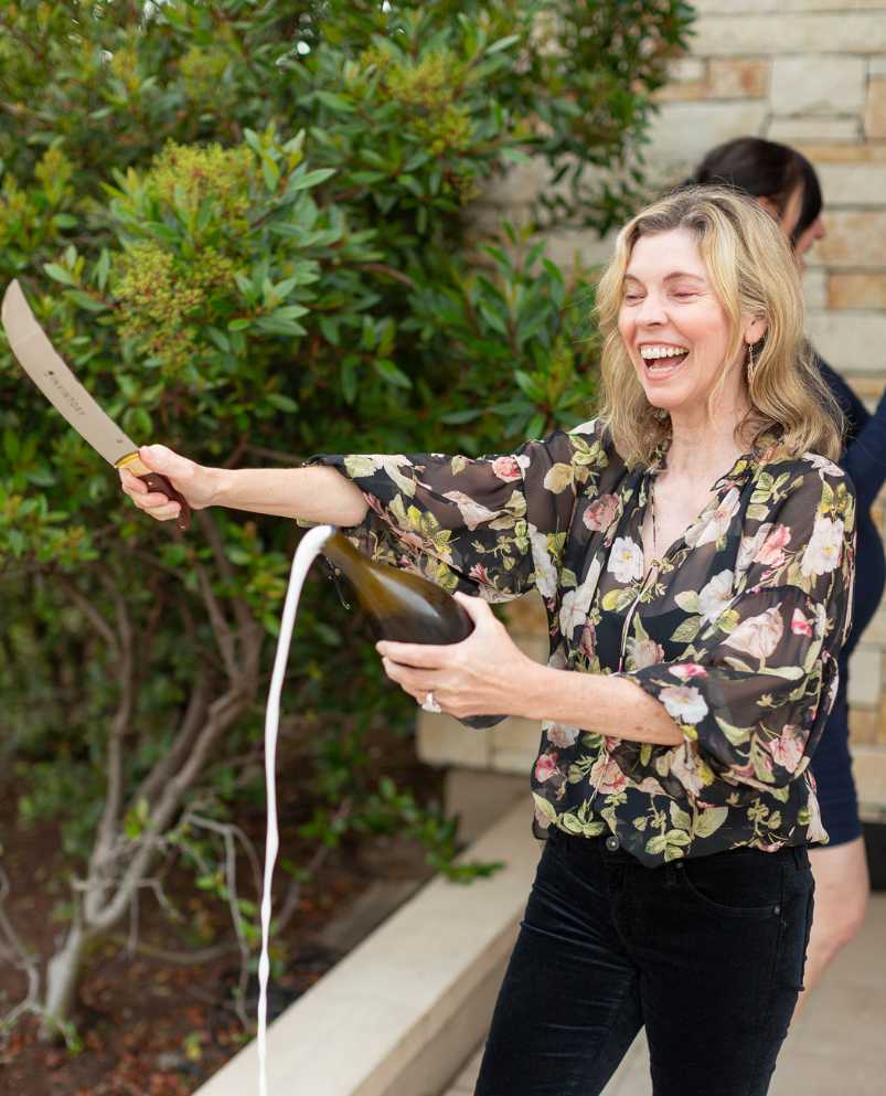 Woman sabering a champagne bottle